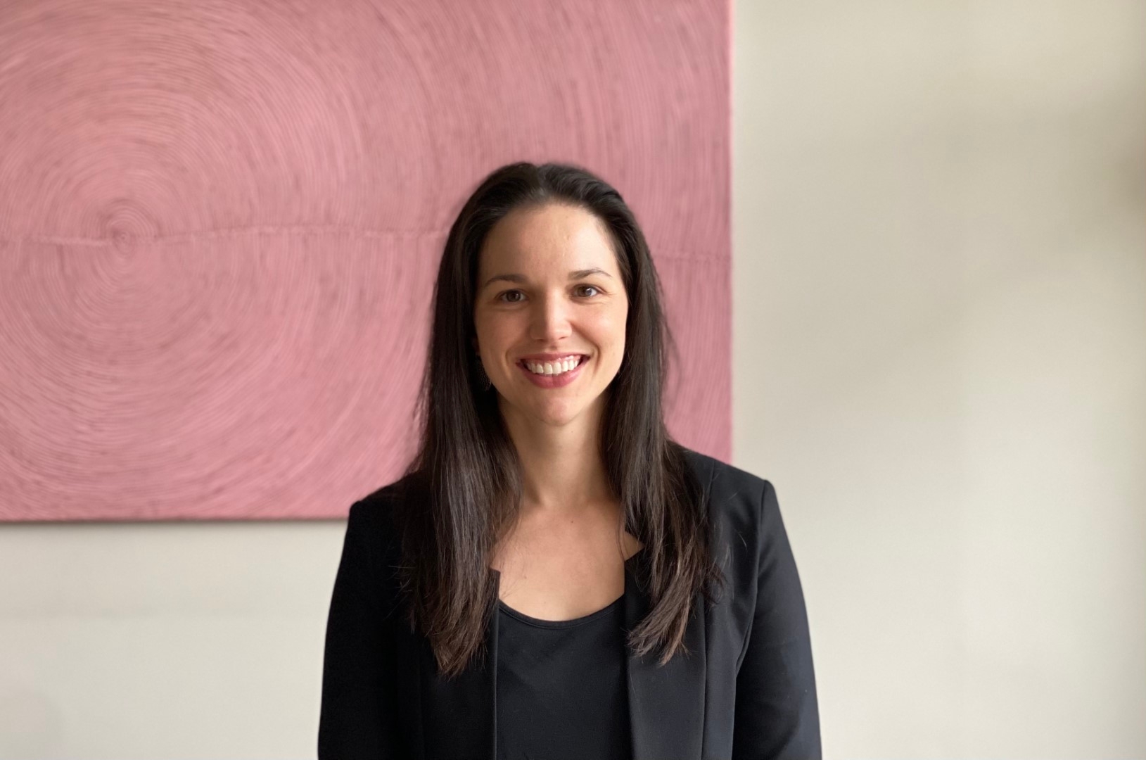 Dr Jessica O'Brien smiling in front of a pink painting