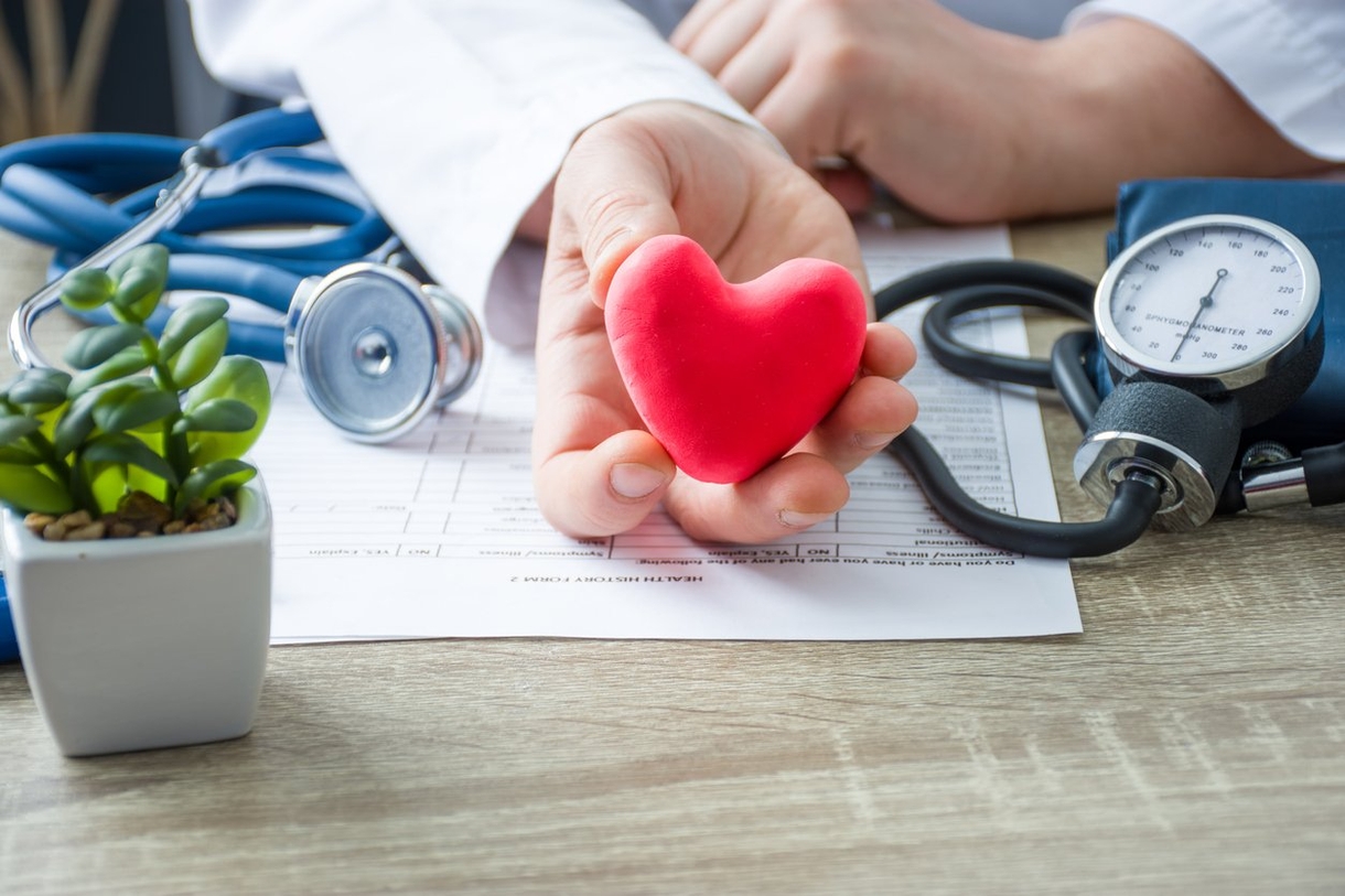 A doctor holding a red heart with a stethoscope, symbolizing care and medical expertise.