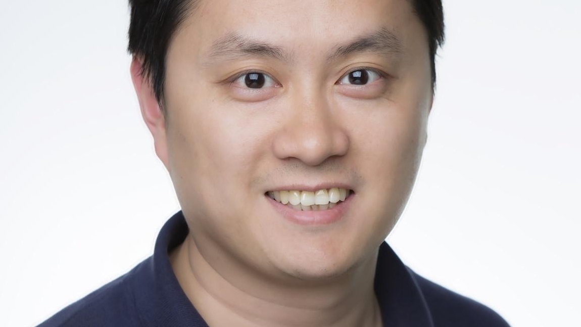 Dr Chenglong Yu smiling, wearing a black shirt.