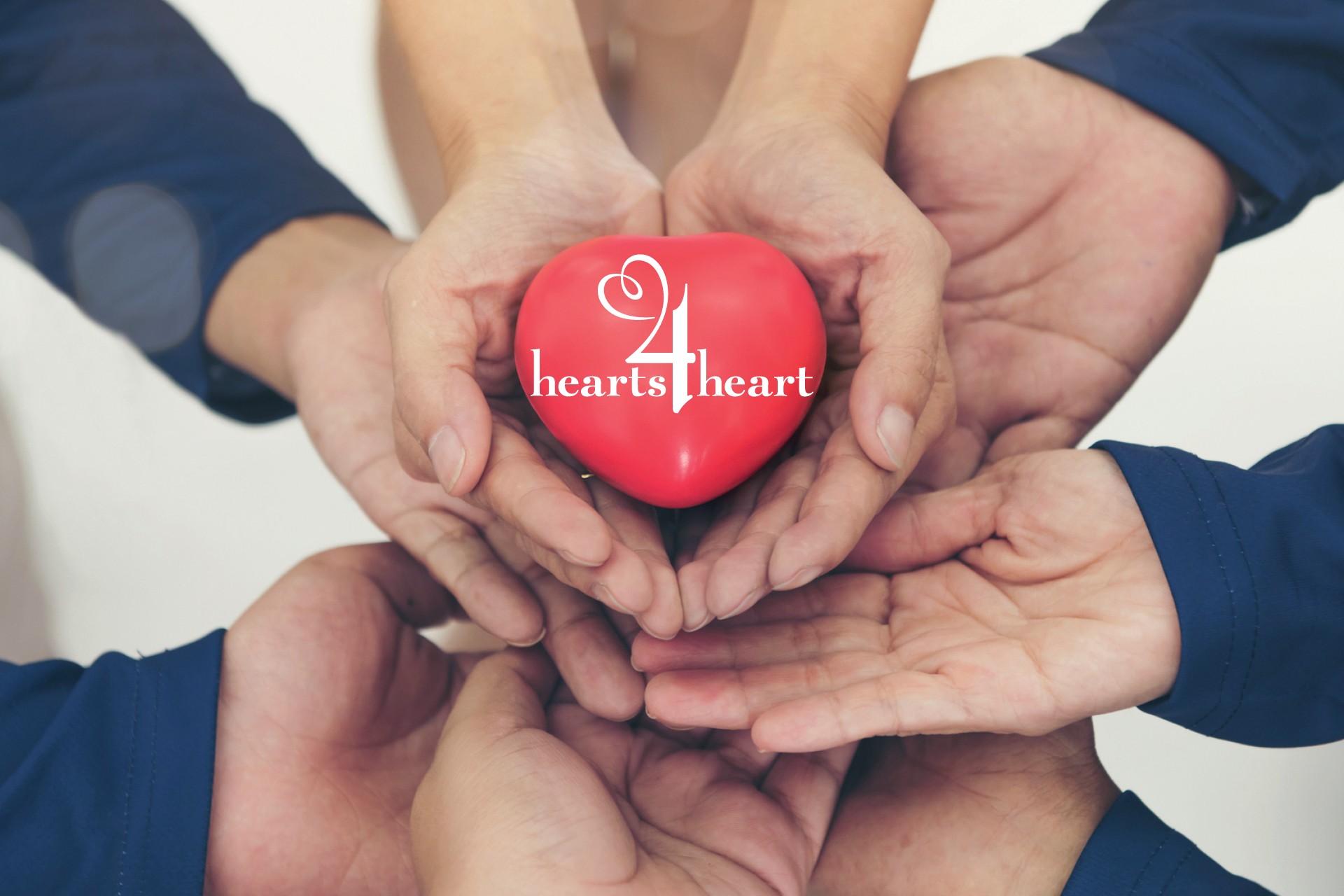 A group of hands holding a heart with the words 'hearts4heart' written on it.