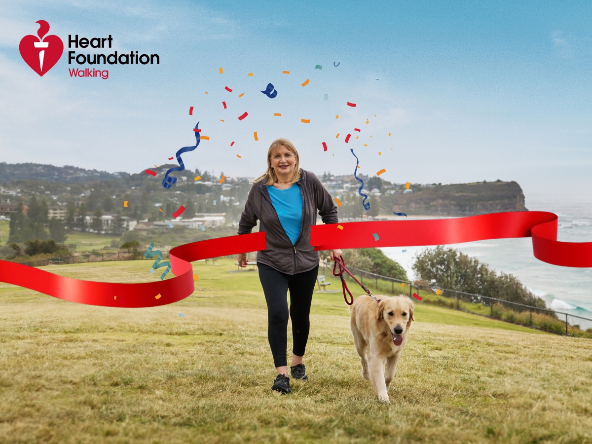 A woman is walking her dog up a hill, with the Heart Foundation Walking logo in the top corner