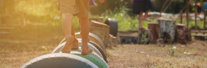 Boy walking across tires in the sunlight