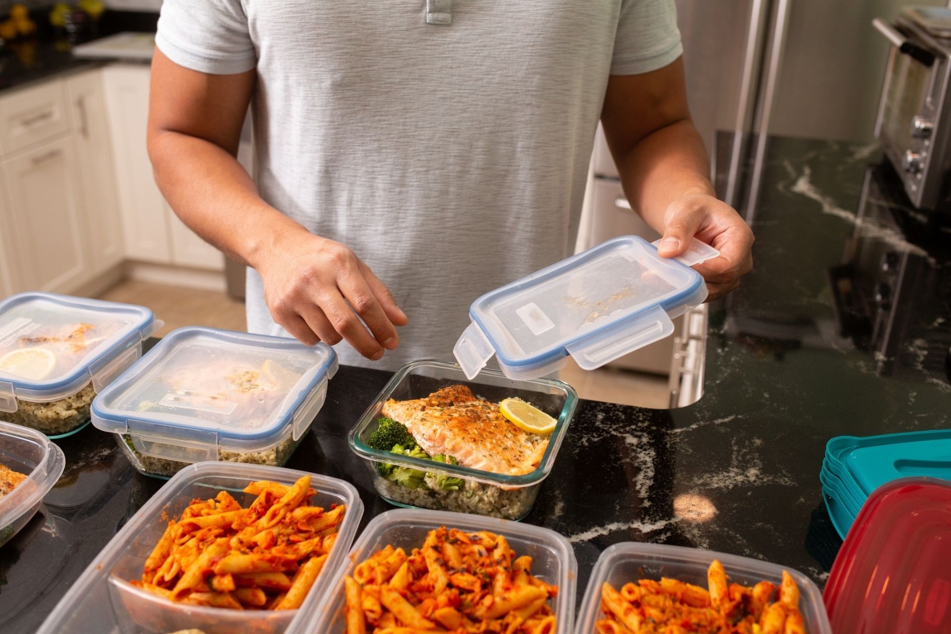 Filipino Man putting away meal prep containers Salmon and Chicken Meat Ball Meal Preps