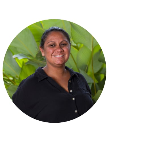 headshot of a women smiling while standing in front of a leafy green background 