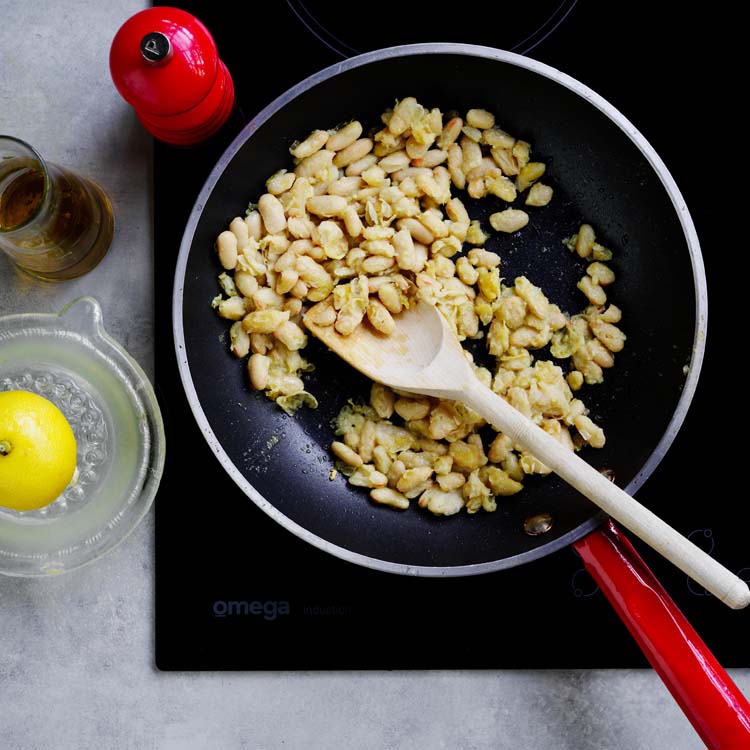 White beans and garlic cooking in a frying pan
