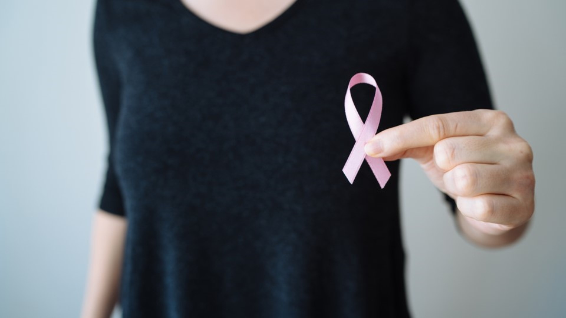 Girl wearing a black tshirt holding a pink ribbon in hand