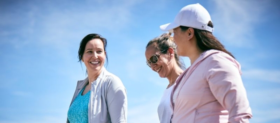 Three happy women chatting and smiling while enjoying a sunny day at the beach