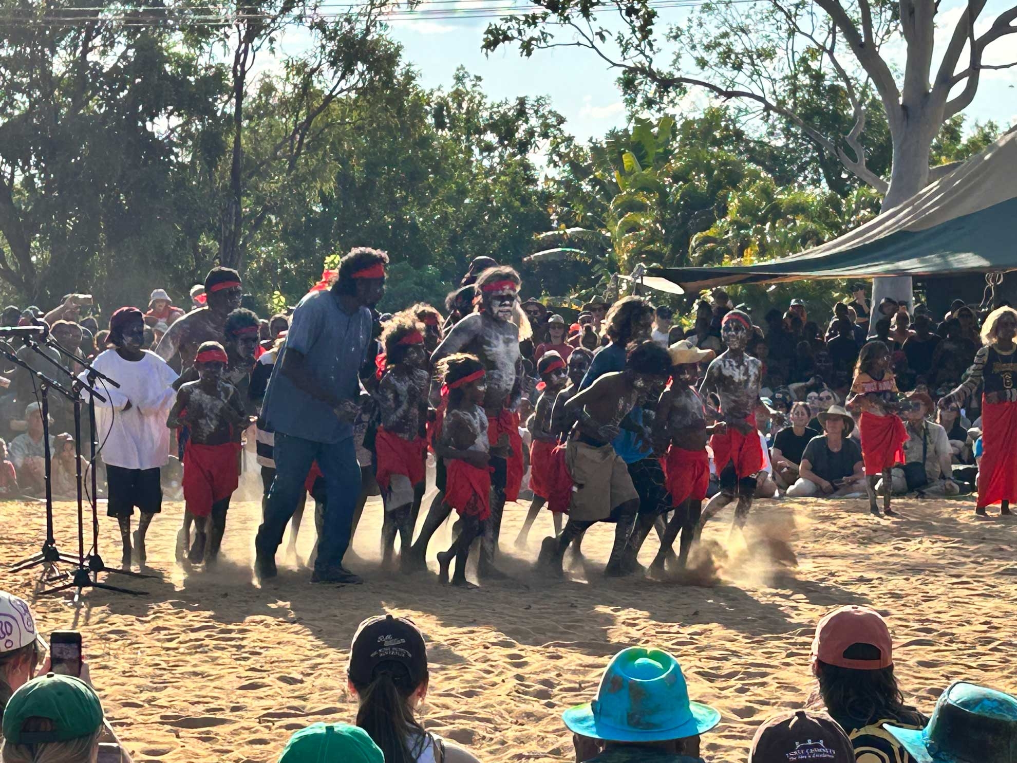 Group of First Nations kids and adults in traditional dance at Barunga Festival 2023