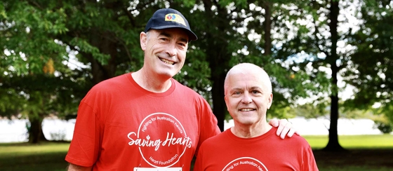 Greg Page and David Lloyd in red t-shirts, smiling together, outdoors