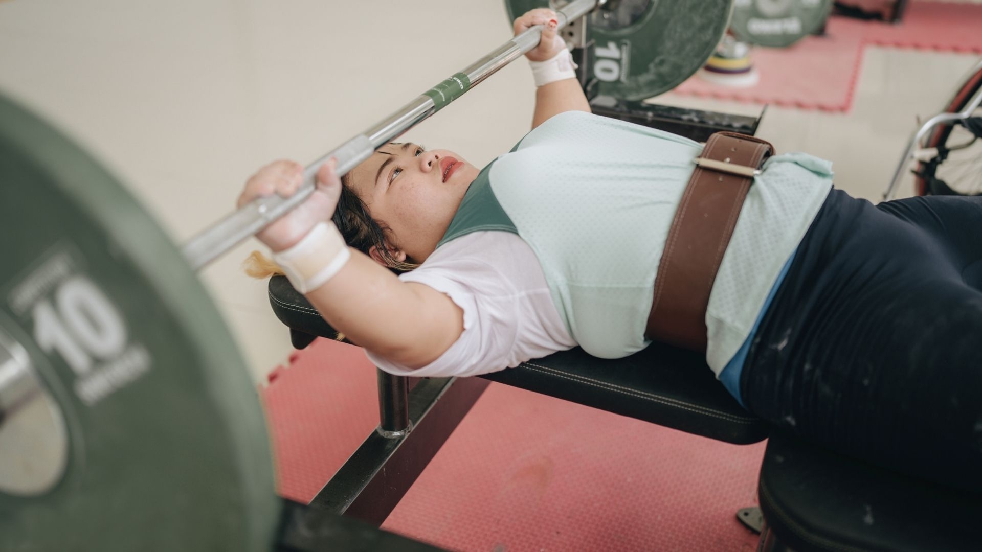 A young disabled woman training on bench press in a gym