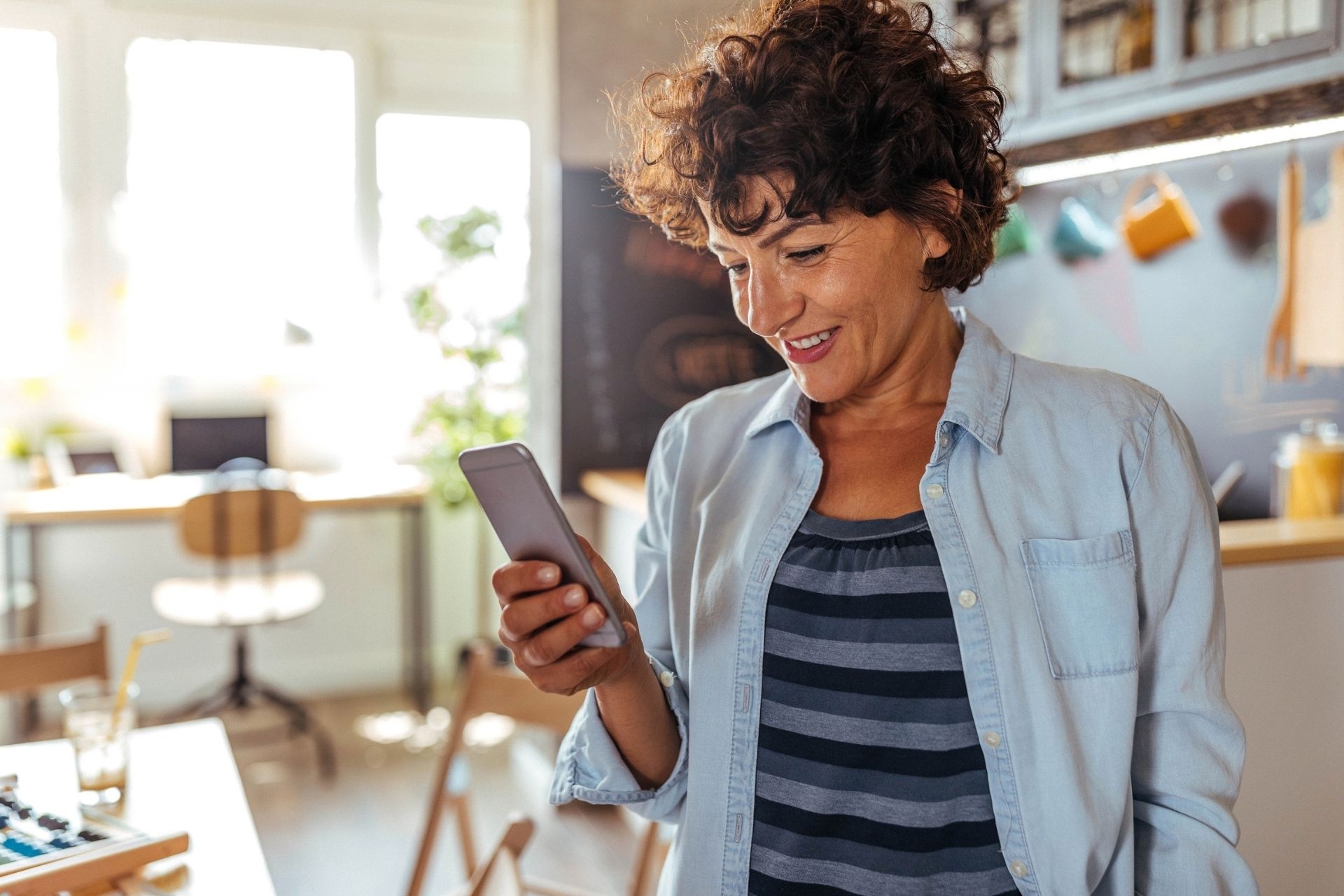 A older woman with curly brown hair, reading a newsletter on her phone.