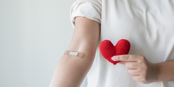 A person getting an INR test done and holding a red heart