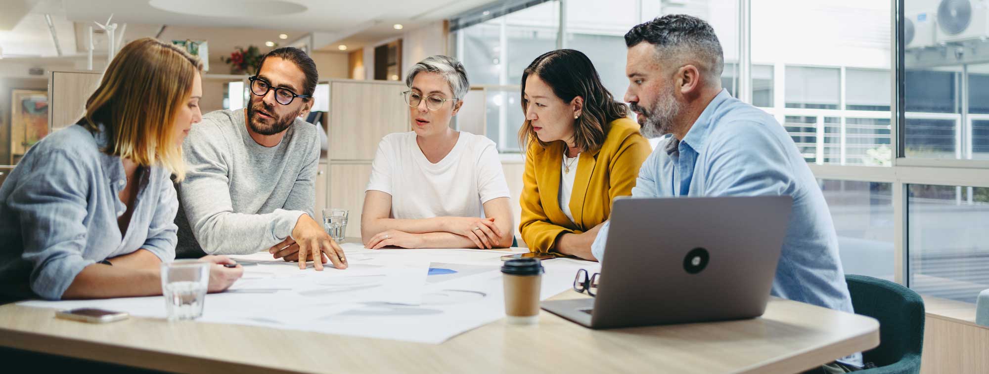 A group of male and female researchers sit around a large table, discussing a project