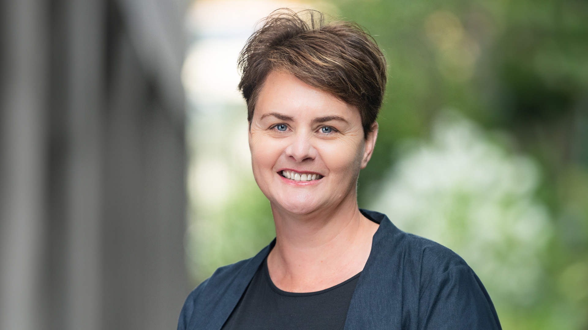 Image of Dr Janet Bray smiling in front of a blurry green background