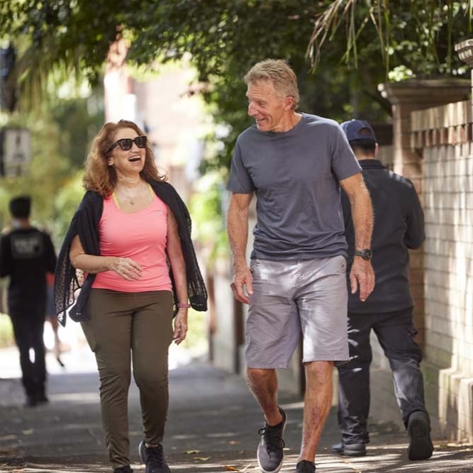 Two people walking together along a shaded footpath