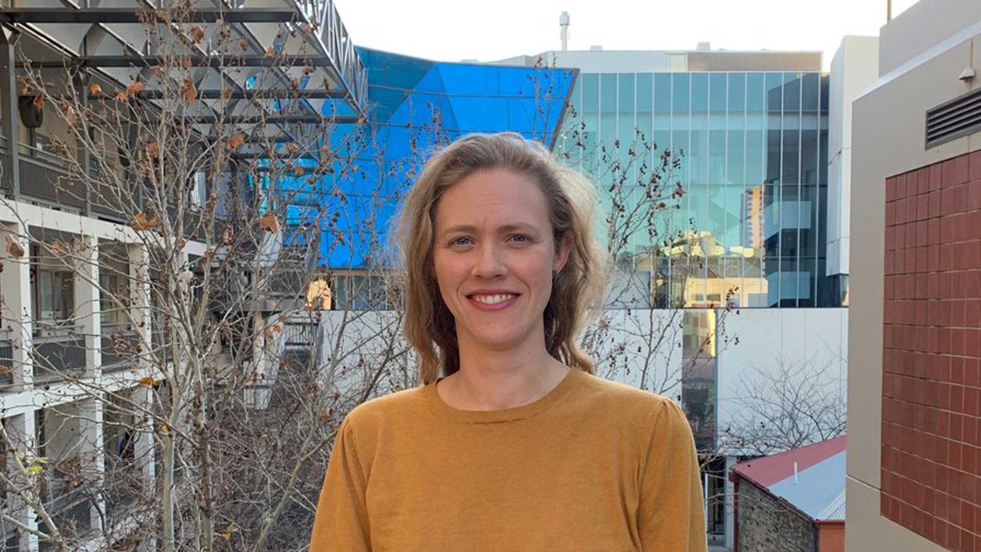Dr Katharine McBride is standing with modern buildings in the background