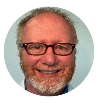 A bearded man with glasses smiling warmly.