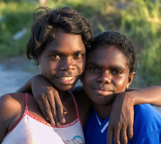Two young Aboriginal girls with arms around each other, close up