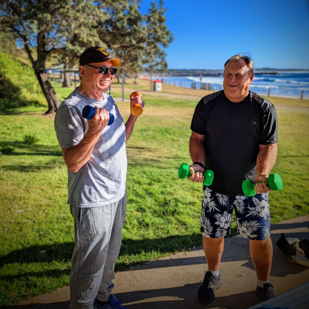 Rob and his friend lifting dumbbells in the park 