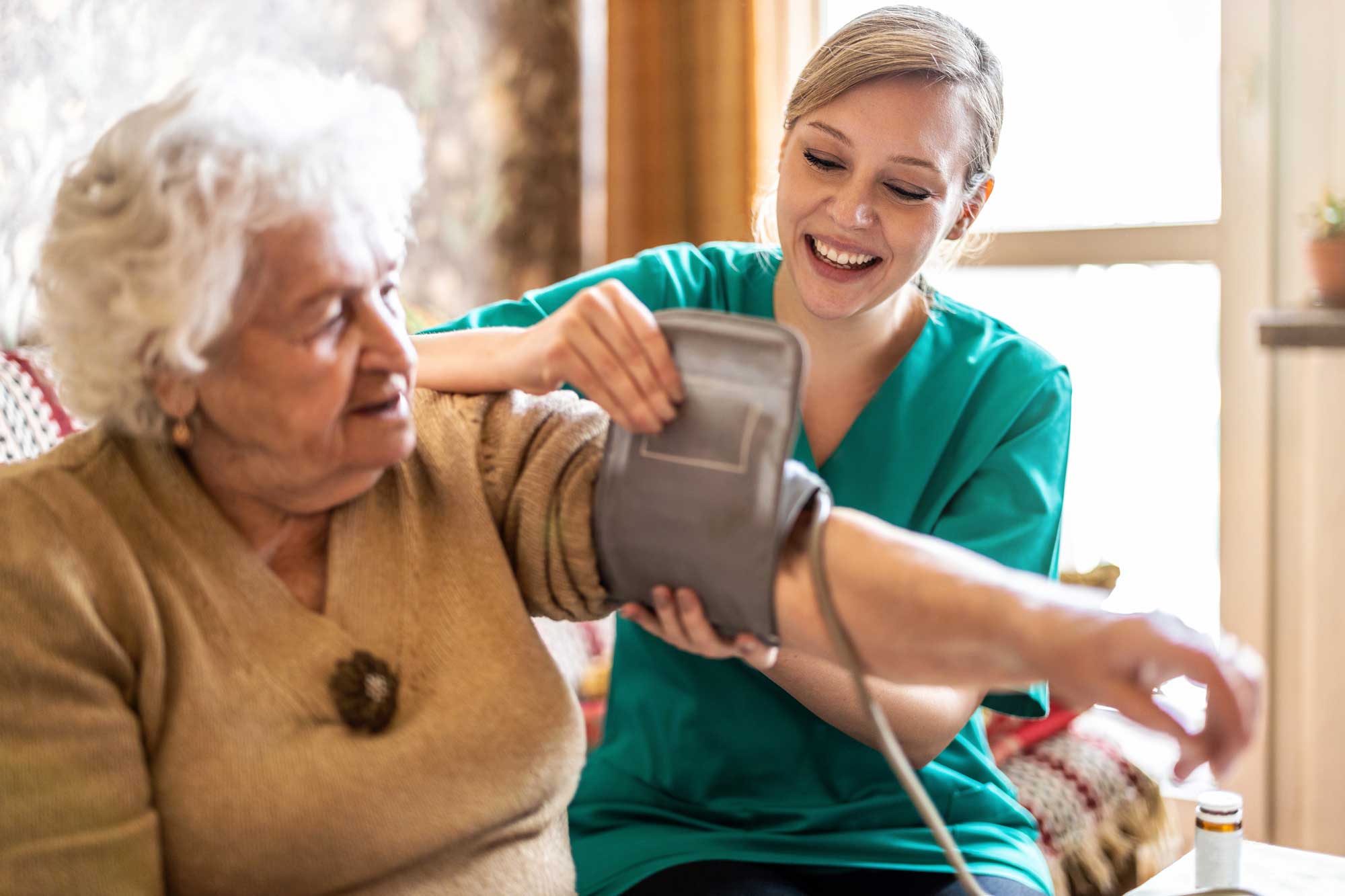 A health professional taking the blood pressure reading of an elderly woman