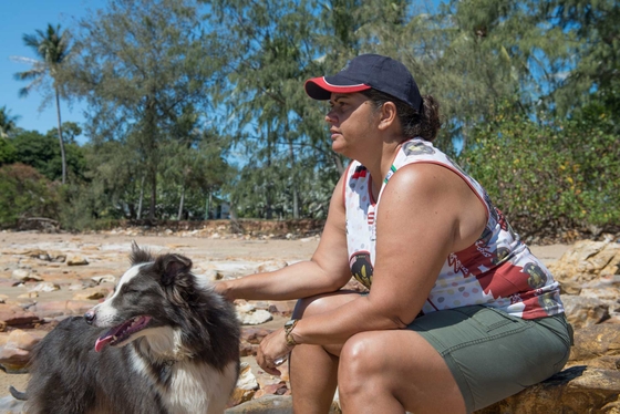 First Nations woman looks out, with her dog 