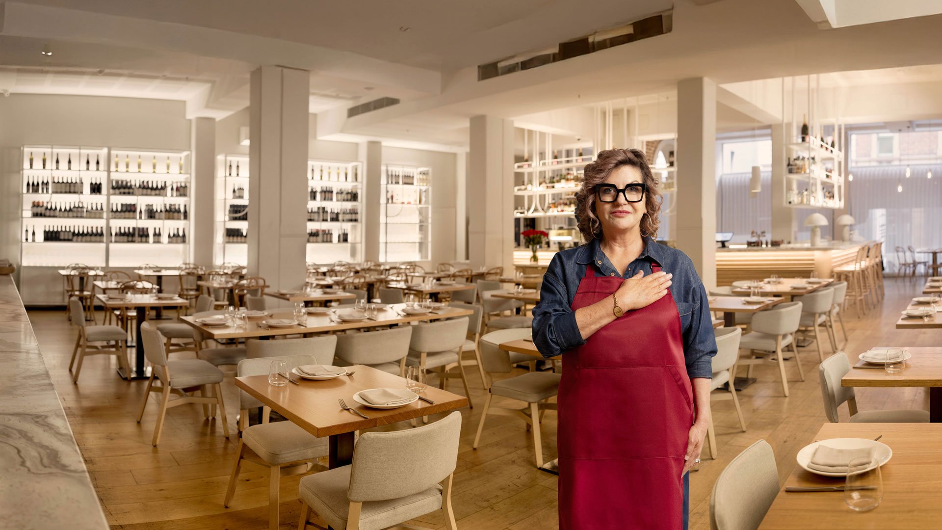 Mandy Hall with hand on heart, in a restaurant