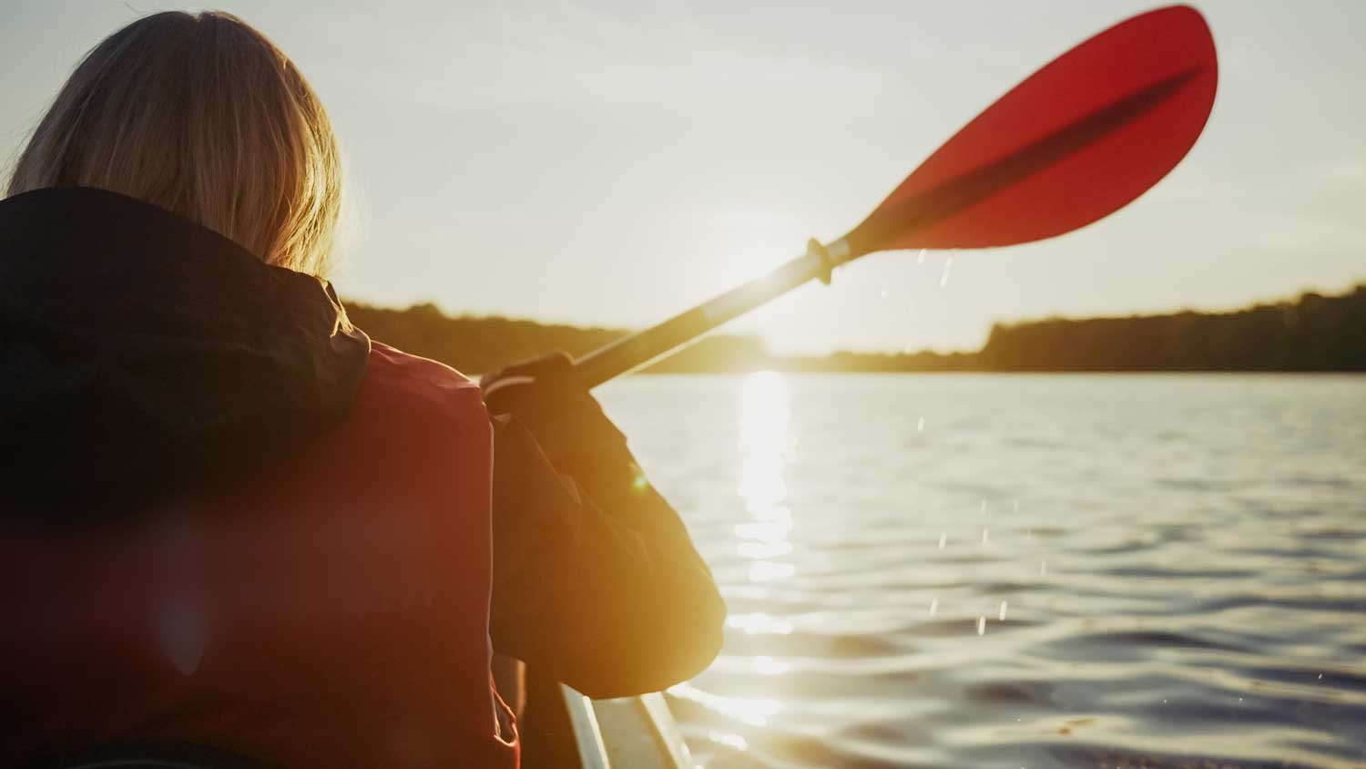Paddler in a kayak on lake at sunrise