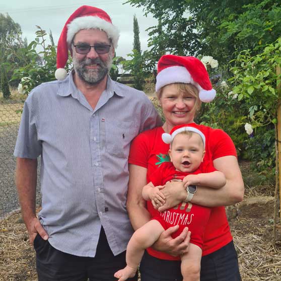 Sharon holding baby with her partner wearing Christmas hats