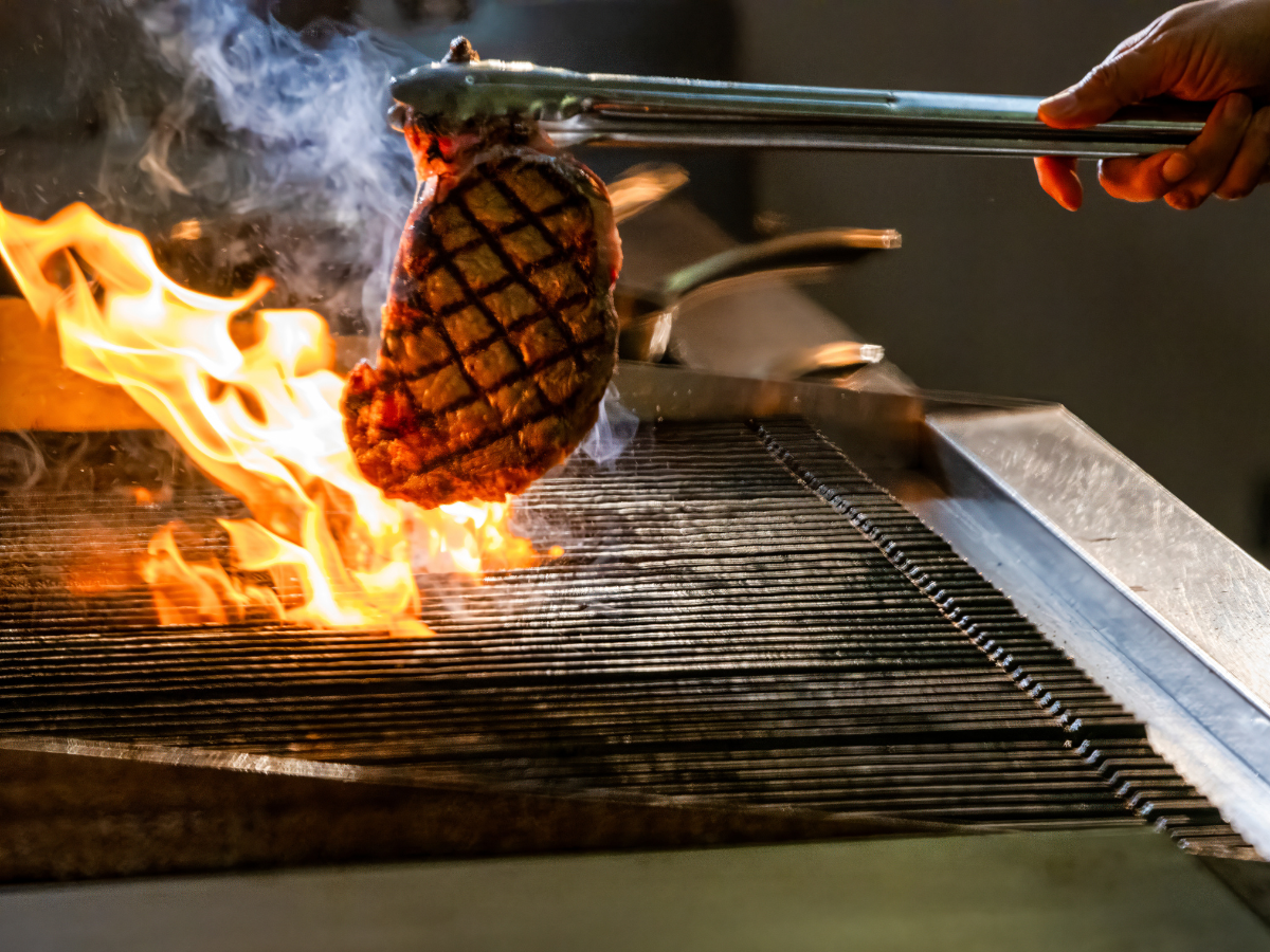 Steak being cooked over high flames