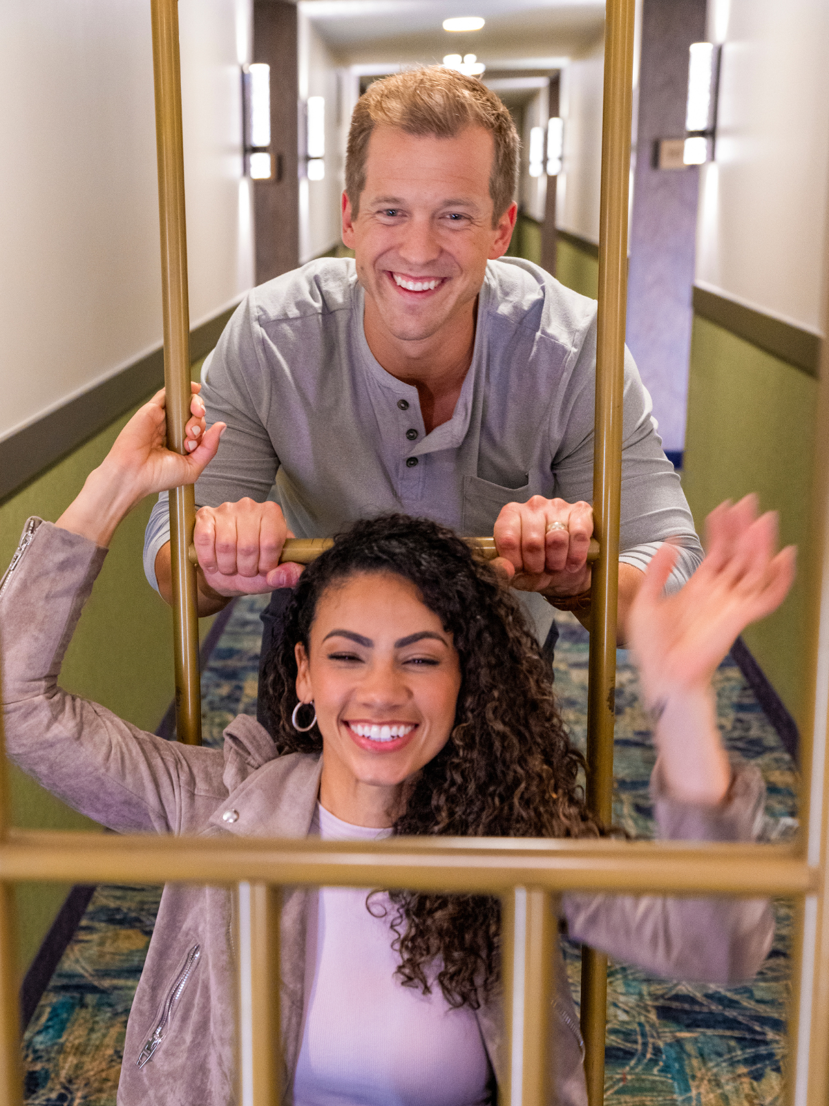 Couple running down hotel hallway on a bell cart