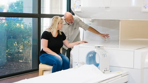 medical professional showing an MRI machine to a female patient