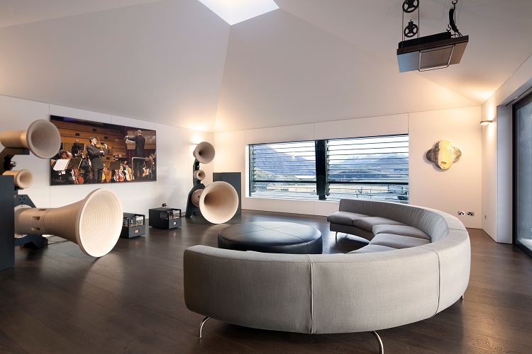 The media and music room features state-of-the-art speakers and a curved pale coloured couch