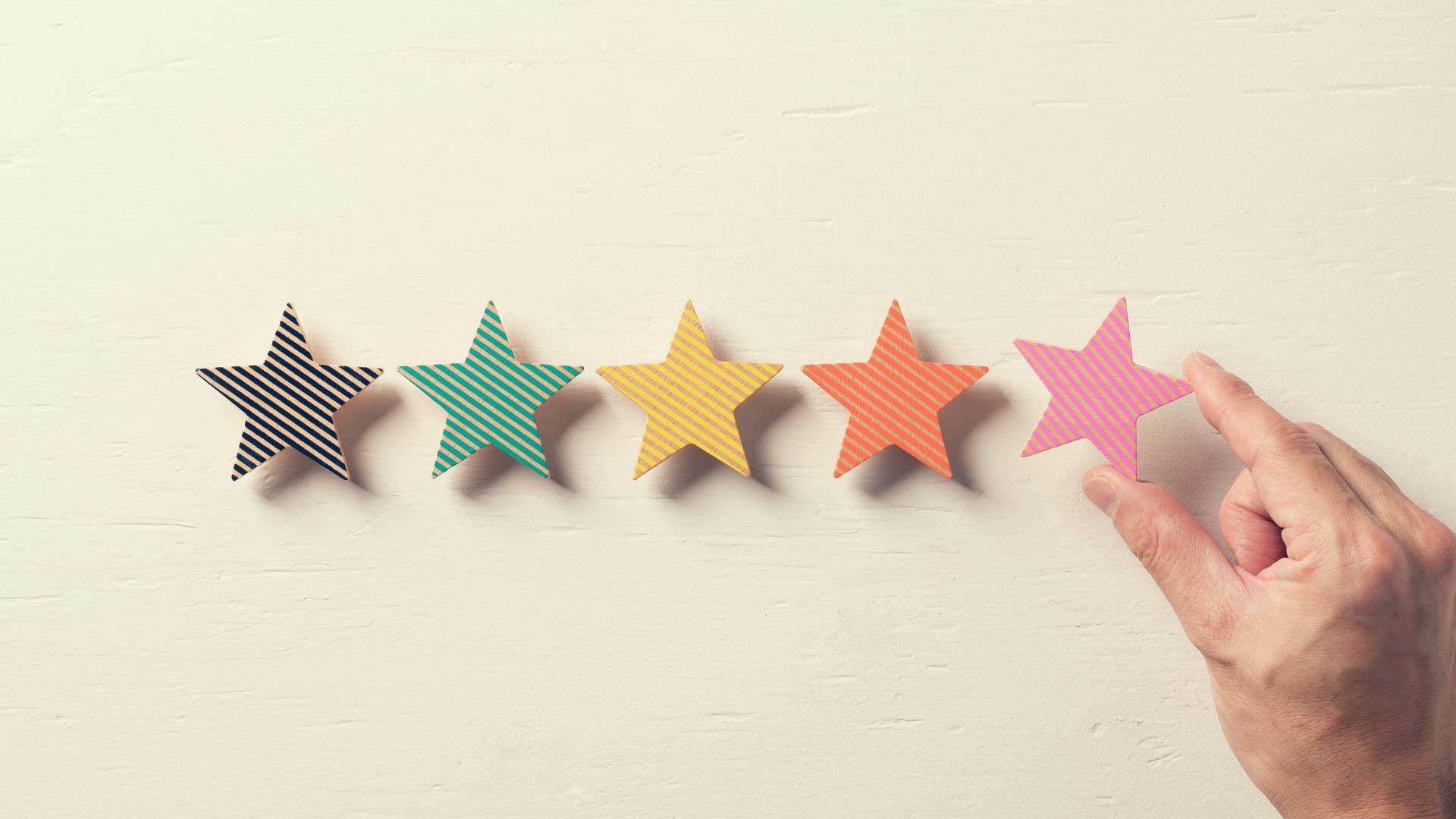 A hand placing a star next to four other stars in a row.