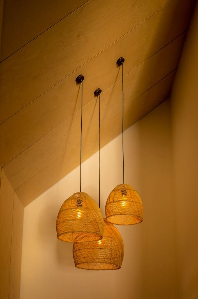 Three designer light fixtures hanging from a gabled ceiling