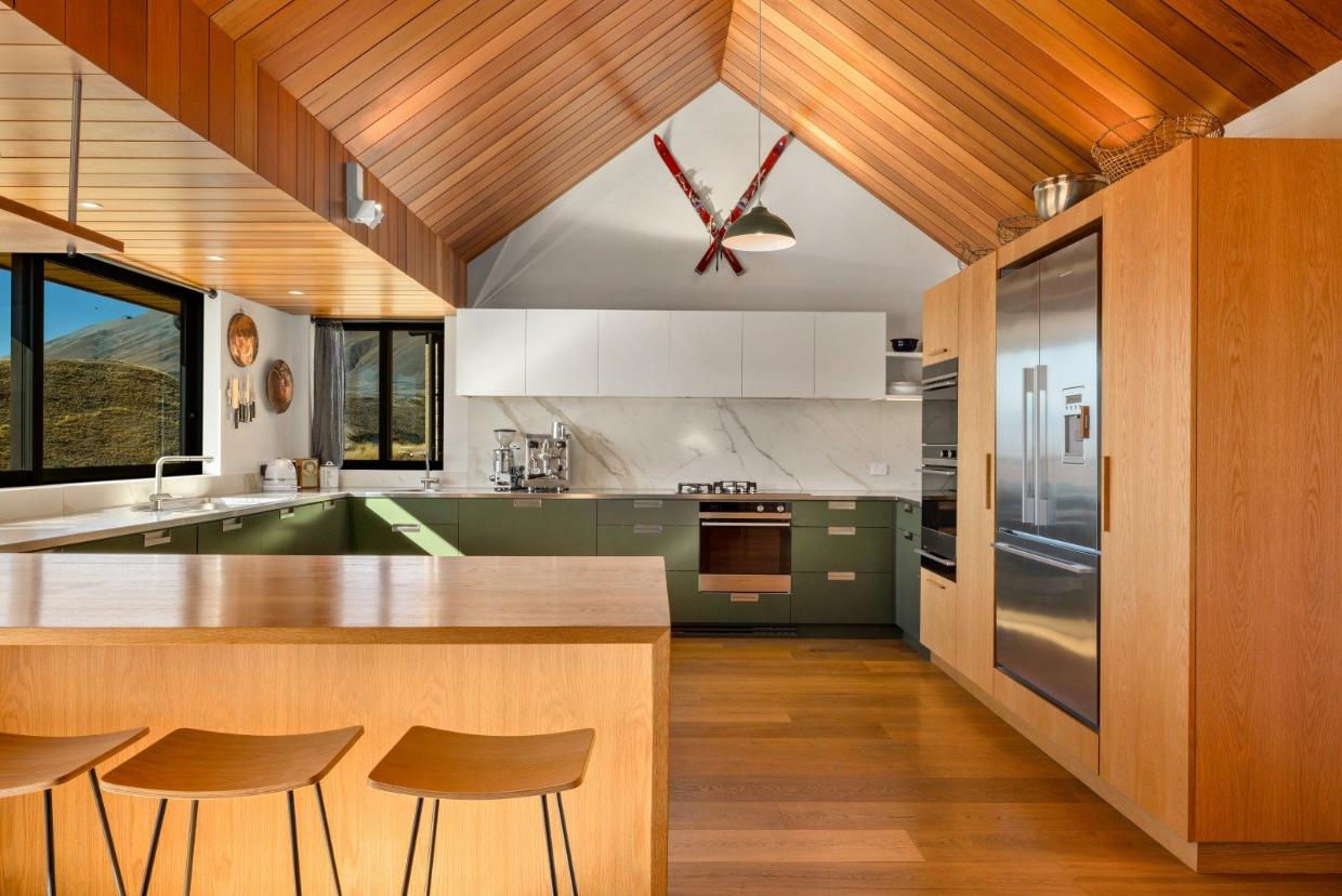 Timber also features in the kitchen, where it is teamed with dark olive green cabinetry. Photo: NZ Sotheby's