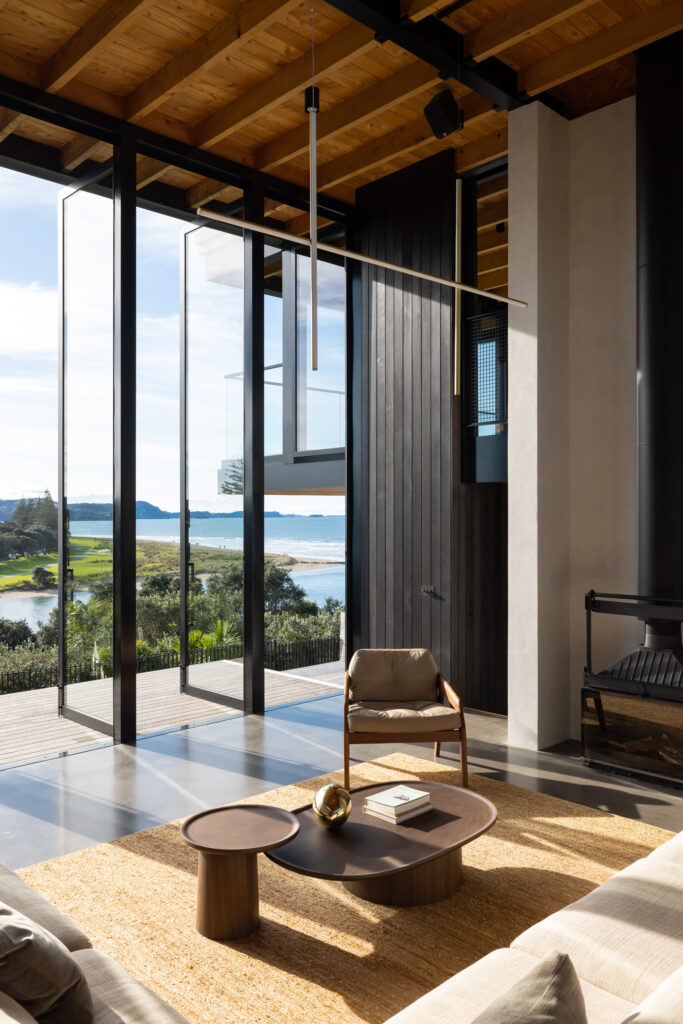 A modern lounge with large windows looking out to a sea view.