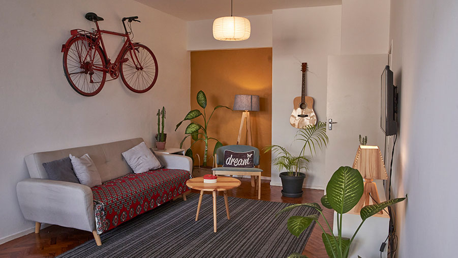 Small living room with a bike and a guitar stored on wall hangers to save space.