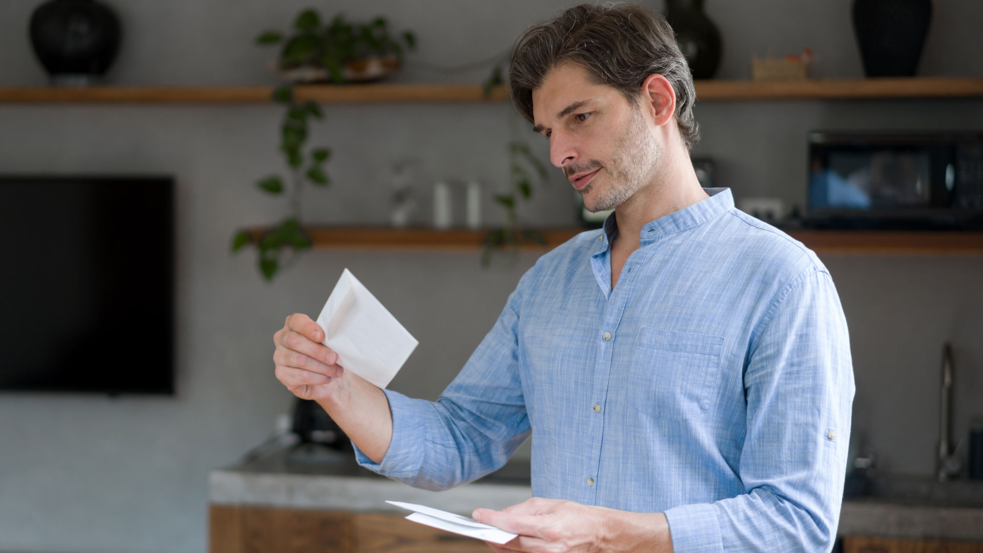 A home seller in NZ reading a tender offer that he has taken from an envelope.