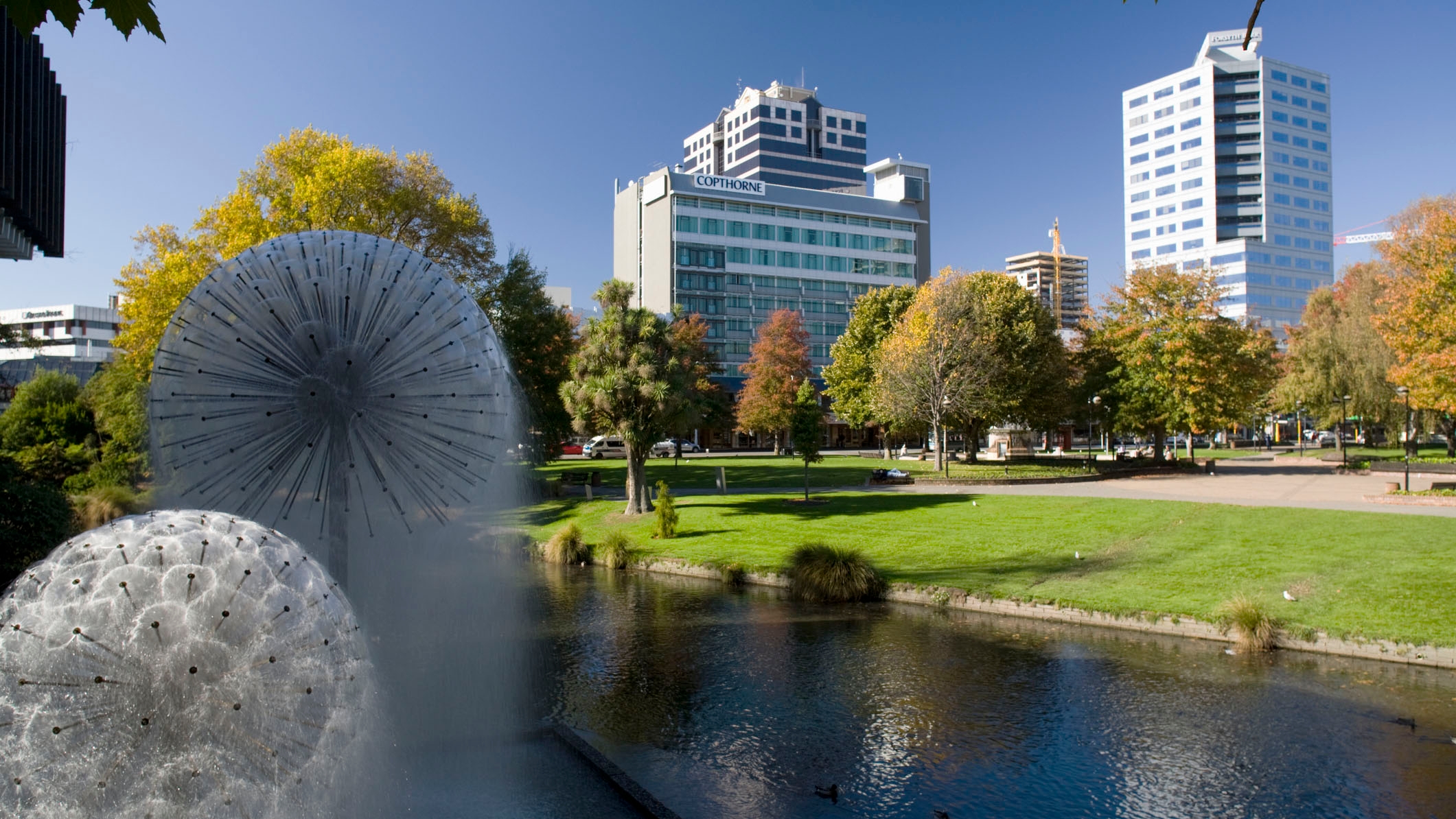 High rise buildings with a park and water fountain in the foreground