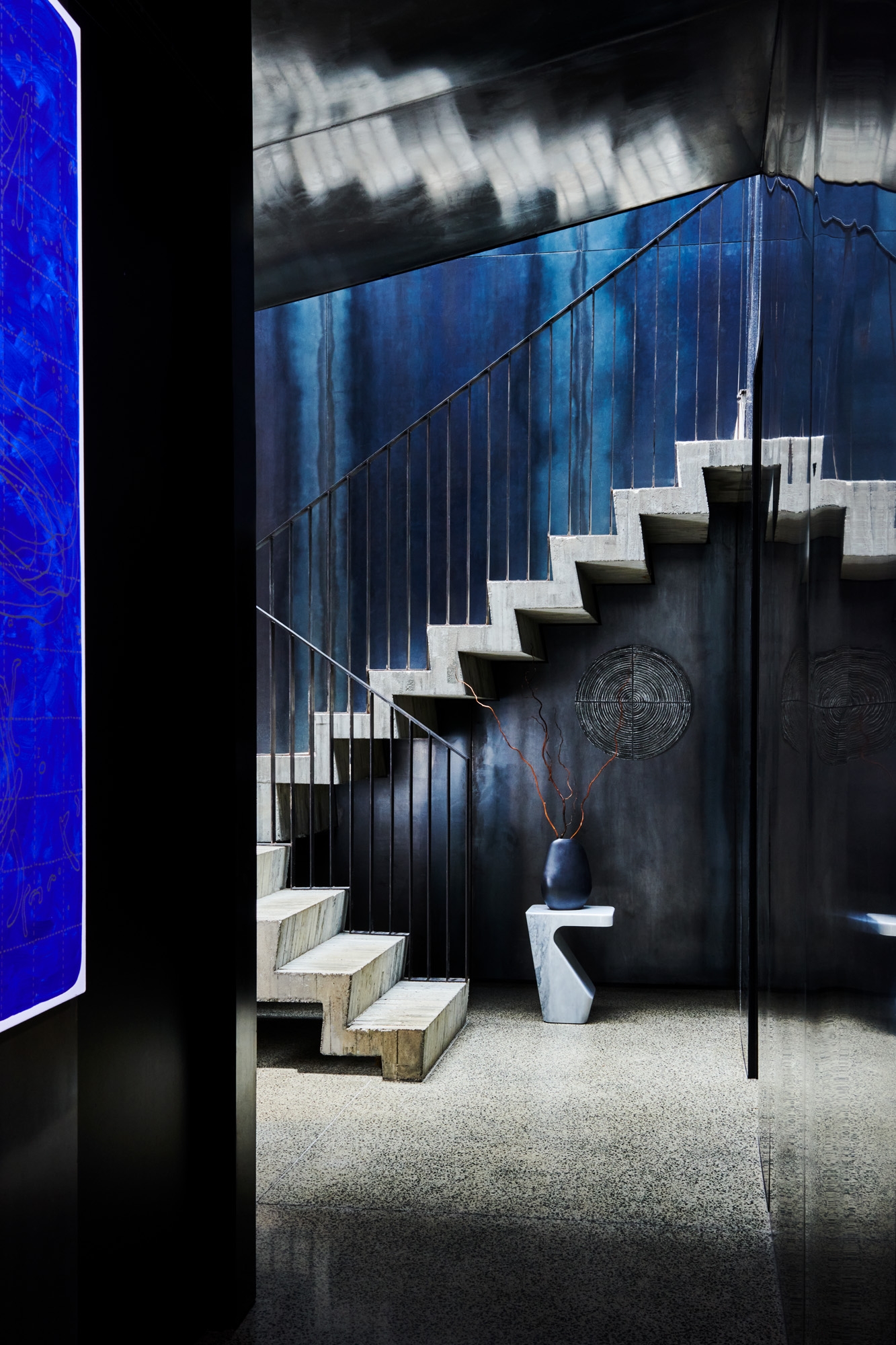 This dramatic stair is defined by art and colour. Here, Whakapapa Disc #1 by Sally Smith is set against a sculptural table, pieces that work perfectly with the surrounding architectural elements.