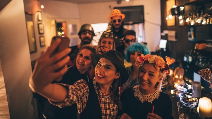 Group of friends in fancy dress at a bar taking a selfie.