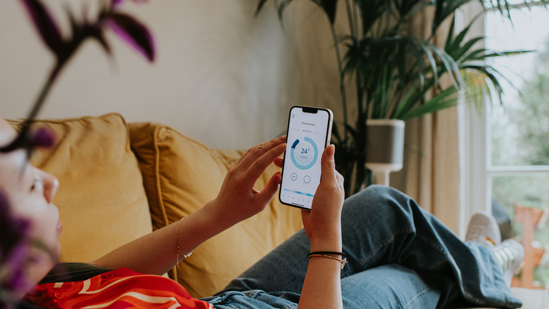 Woman adjusting her smart thermostat on her phone at home.