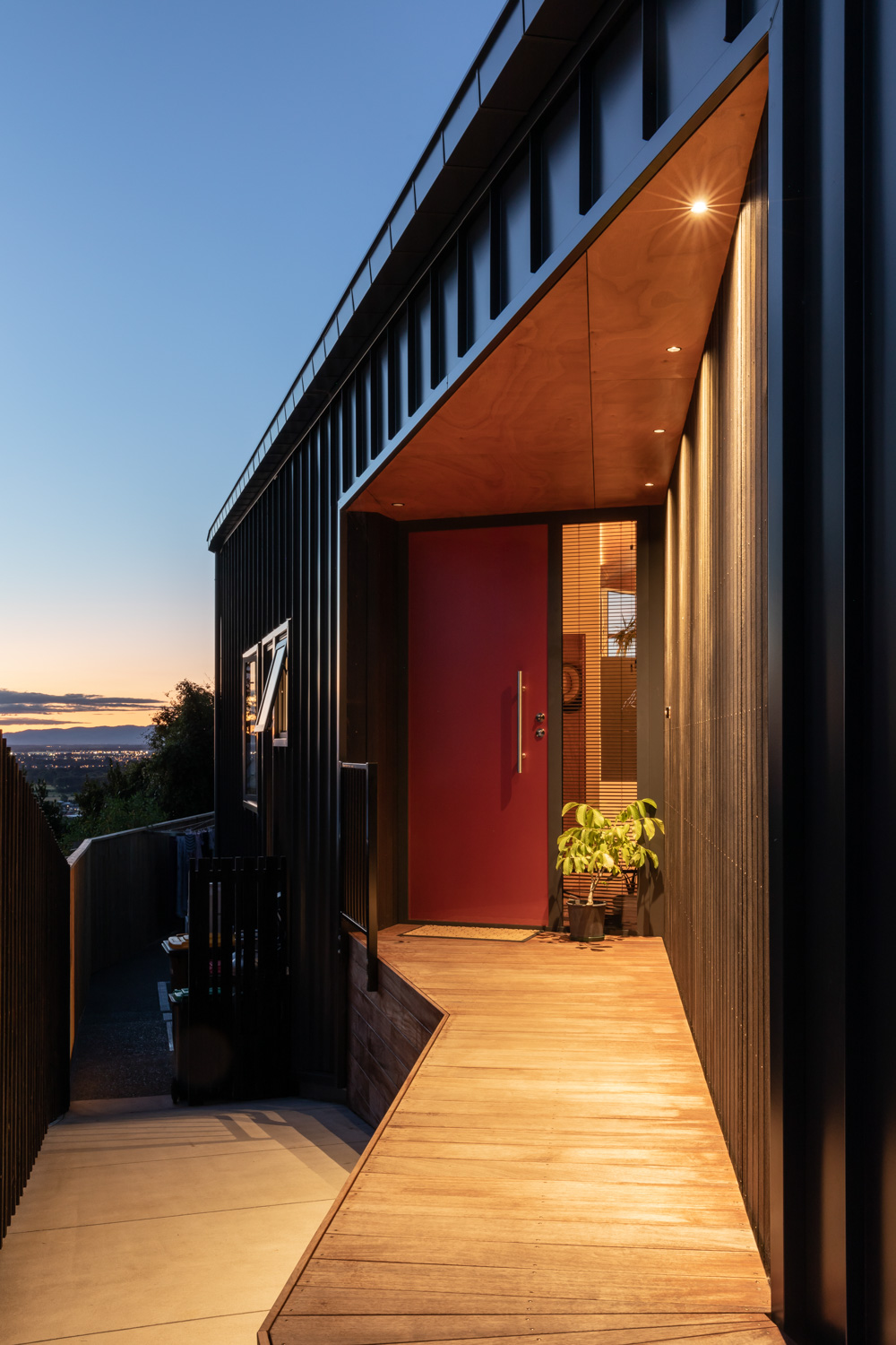 Modern house shows a door and walkway that has been well lit. Industrial and wooden look