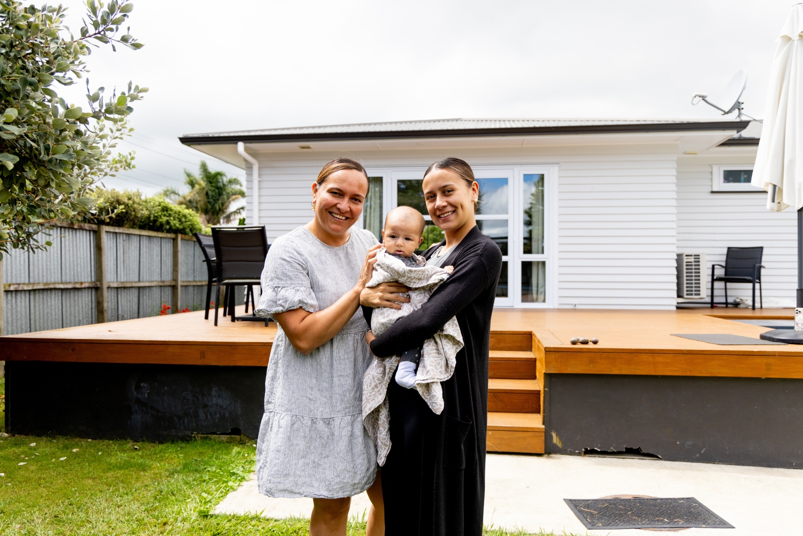 Couple holds their baby outside their house