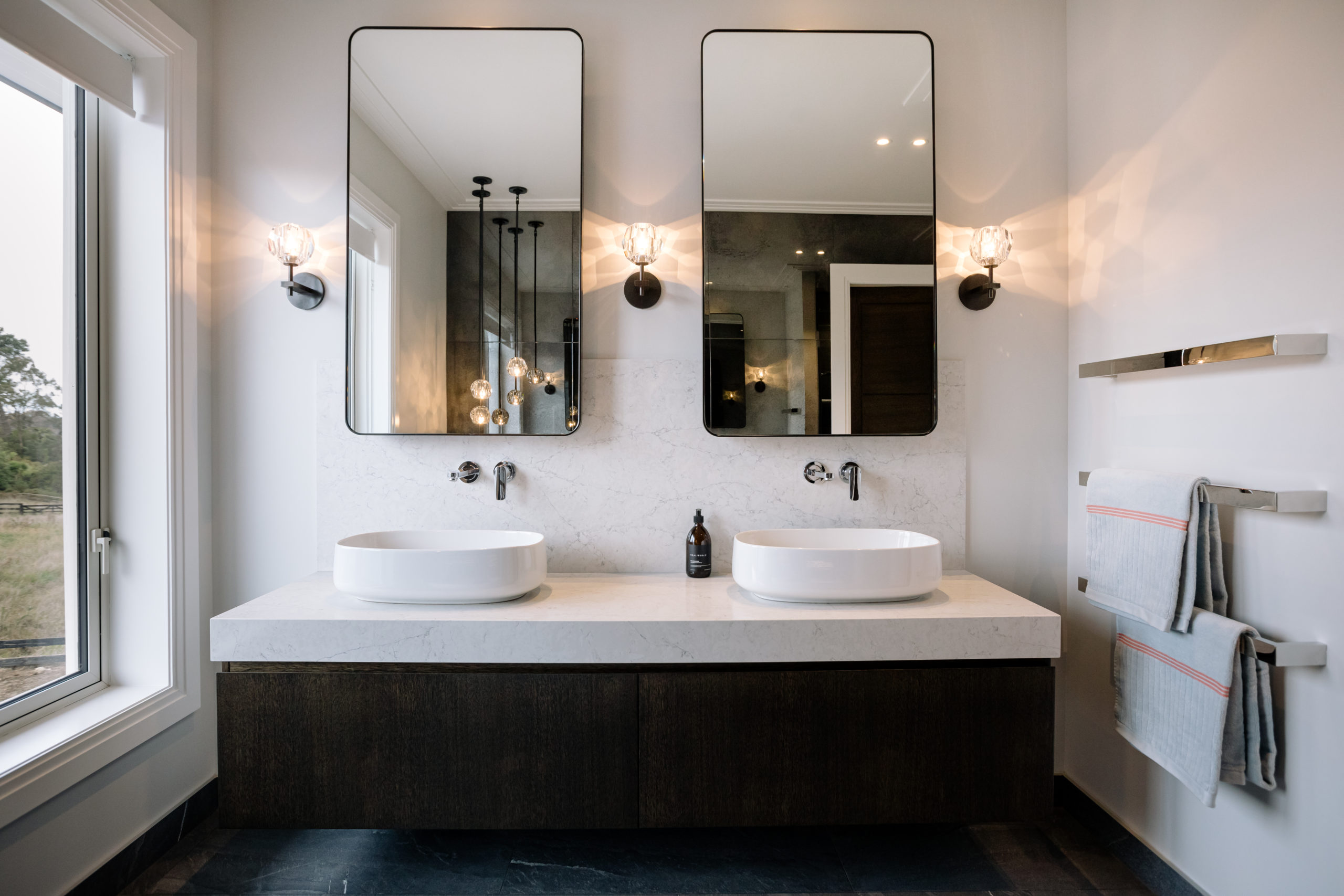 With their rounded corners echoing the curves of the sinks, and flanked by wall sconces, these mirrors add a feminine touch to this ensuite bathroom. Photo above - Kelsie Barley