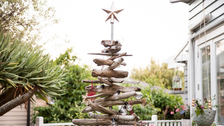 Christmas tree made of stacked driftwood with a star decoration on top. The tree is also covered in handmade and natural decorations.