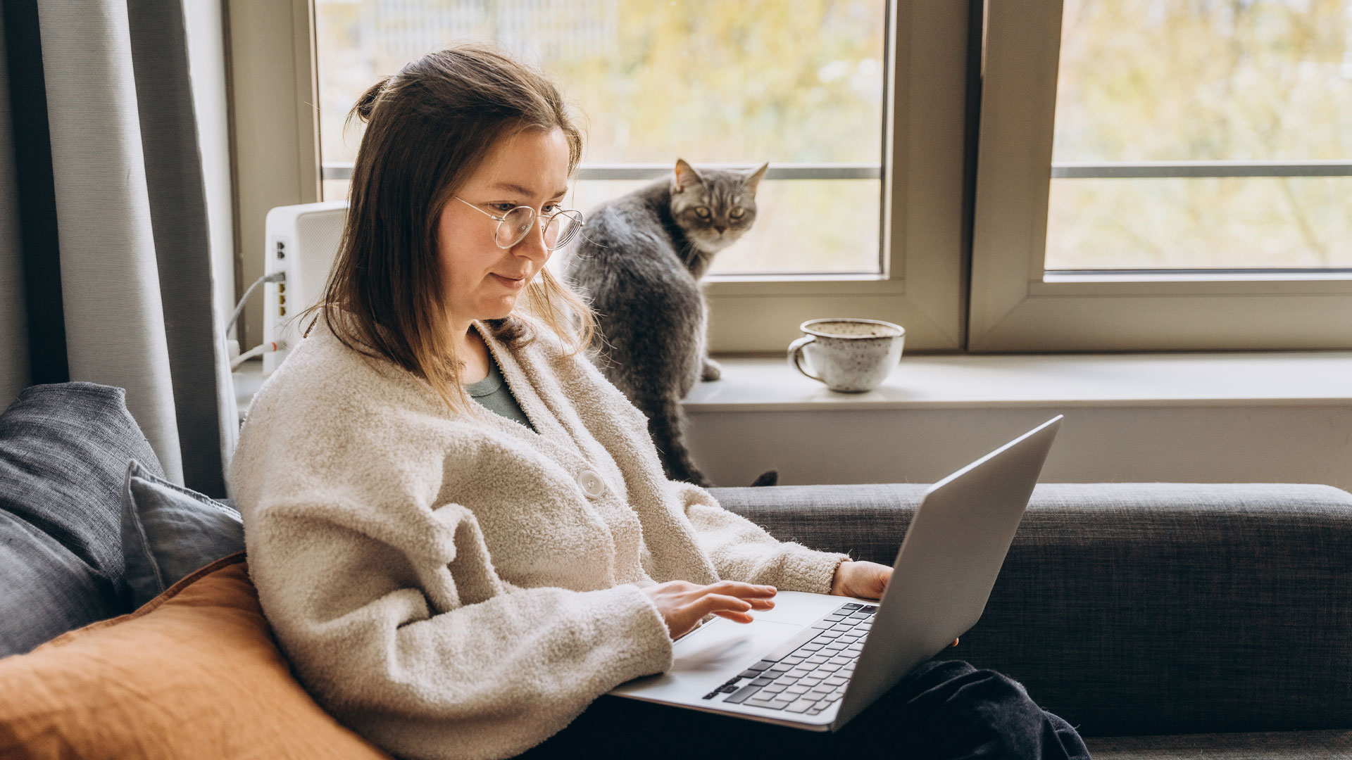 Woman searcing for a new job on Trade Me Jobs on her laptop, at home, with her cat.