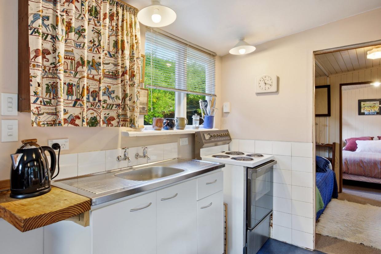 The kitchen unit sits against one wall, and there are still wall-mounted taps. Photo: Nidd Realty