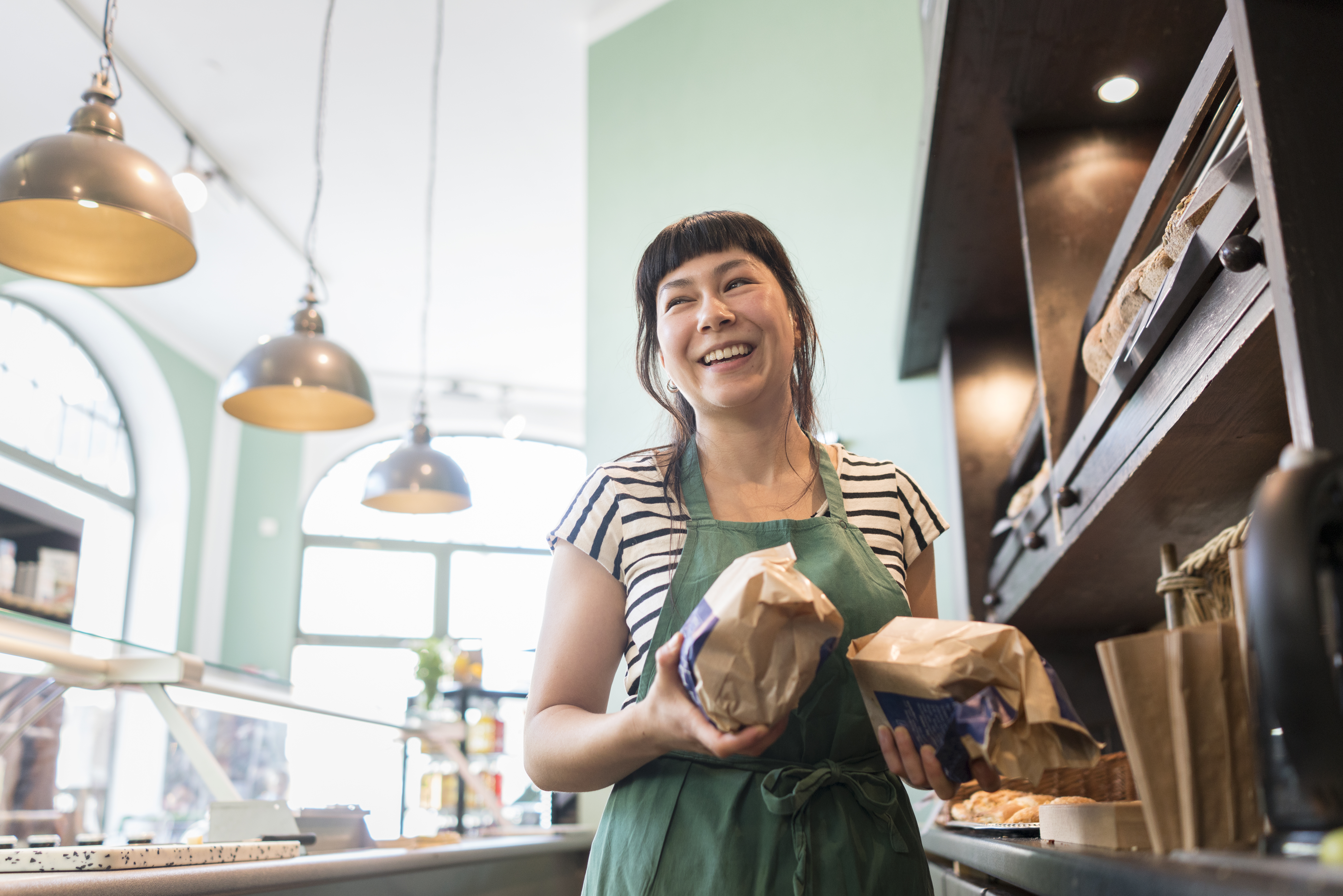Female hospitality worker smiling holding loaves of bread