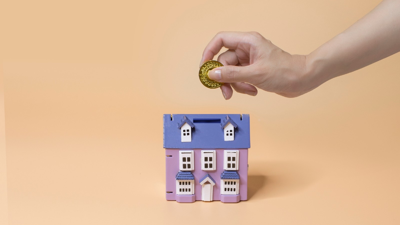 How to pay mortgage off faster. Person putting coin into house.